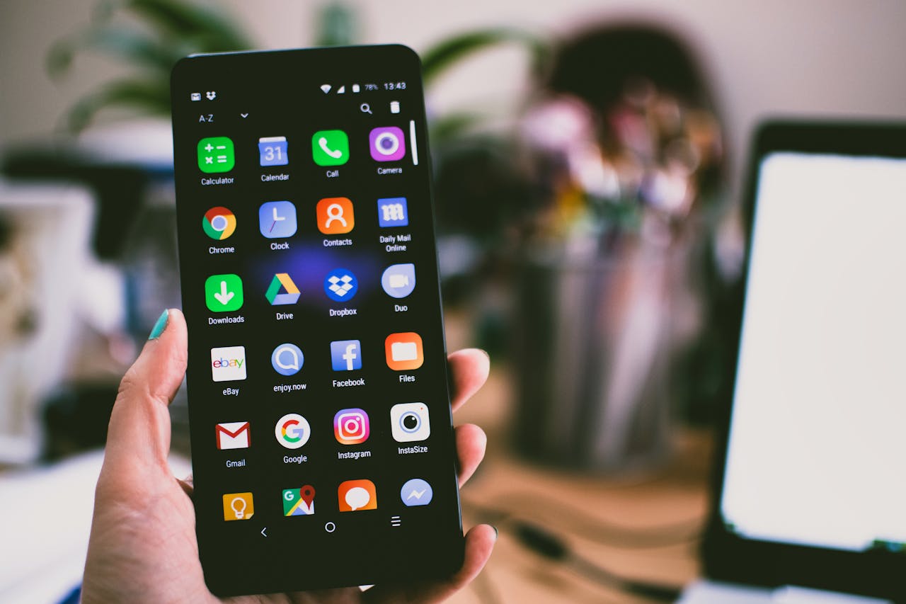 about-img A close-up image of a person's hand holding a smartphone displaying various popular apps.