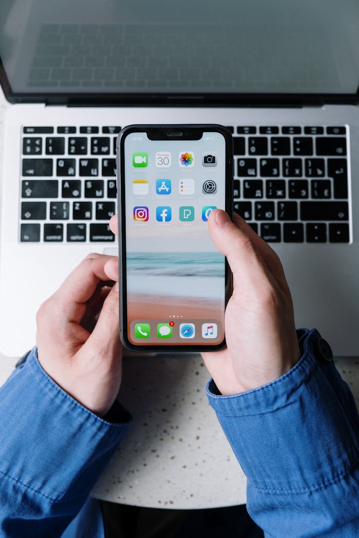 The Art of Drawing Readers In: Your attractive post title goes here Close-up view of hands holding a smartphone with apps over a laptop keyboard.