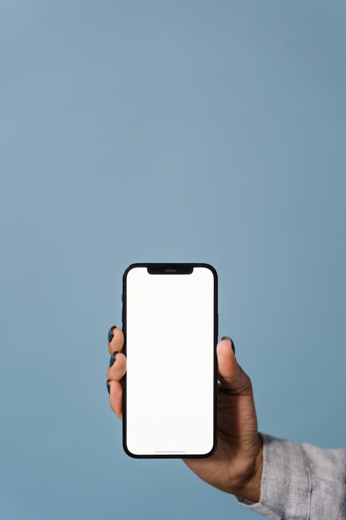 Mastering the First Impression: Your intriguing post title goes here Close-up of a hand holding a smartphone against a blue background, showcasing blank screen.